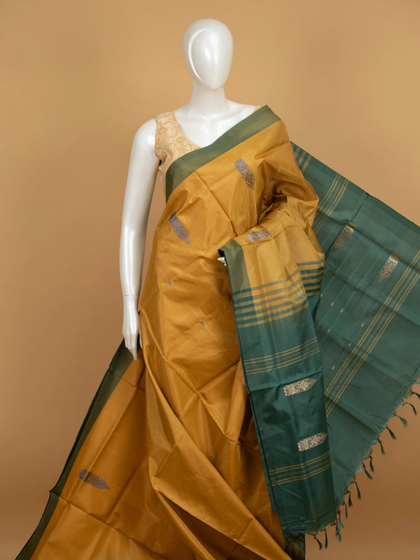 Mustard banana silk saree with contrast bottle-green border, gold zari buttas and striped tasselled pallu