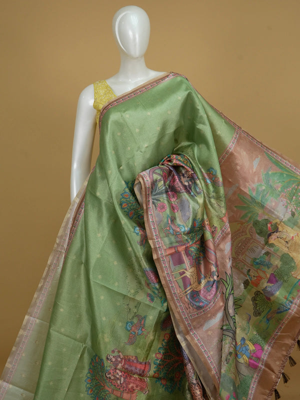 Green semi tussar saree with gold zari border, zari buttas and a multicolour Kalamkari printed pallu with a copper brown floral blouse