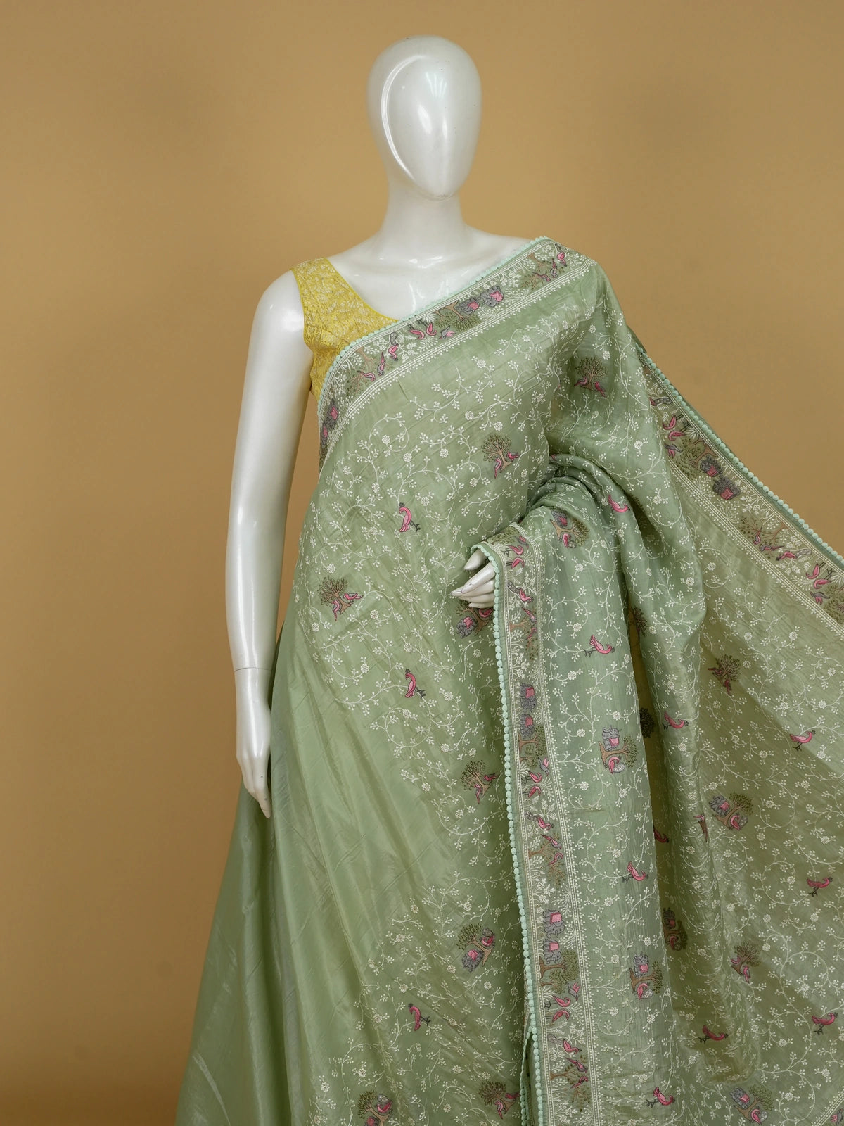 Sage green designer saree with white floral embroidery, pink bird and elephant motifs and pom-pom lace border