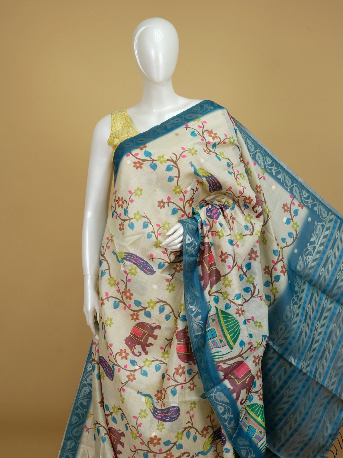 Cream linen cotton saree with peacock and elephant motifs and a teal silver zari border