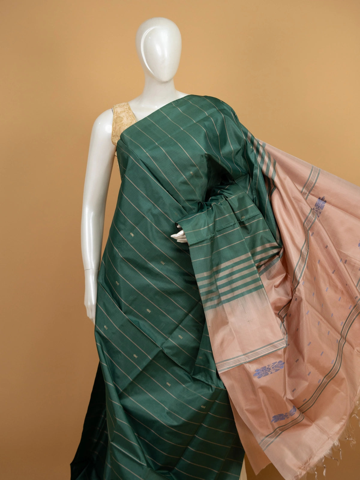 Dark green banana silk saree with gold zari stripes and contrast peach pallu with blue floral motifs