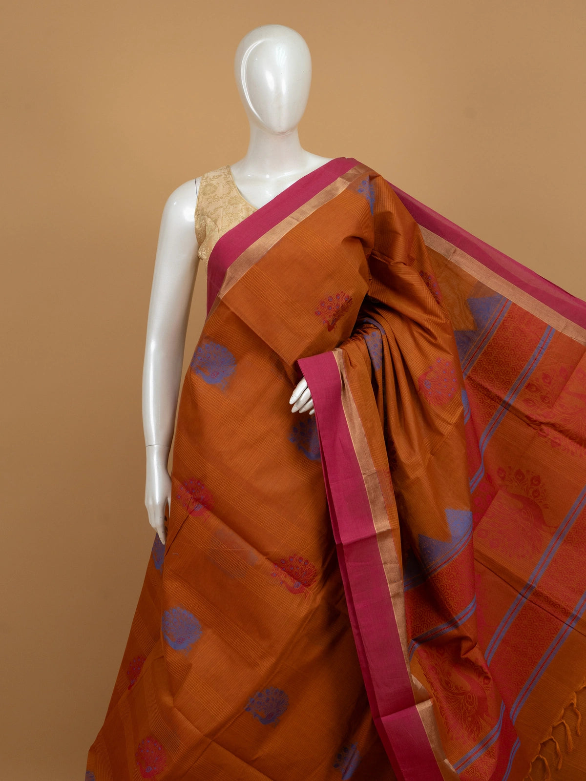 Rust orange silk cotton saree with pink zari border and blue and red peacock motifs