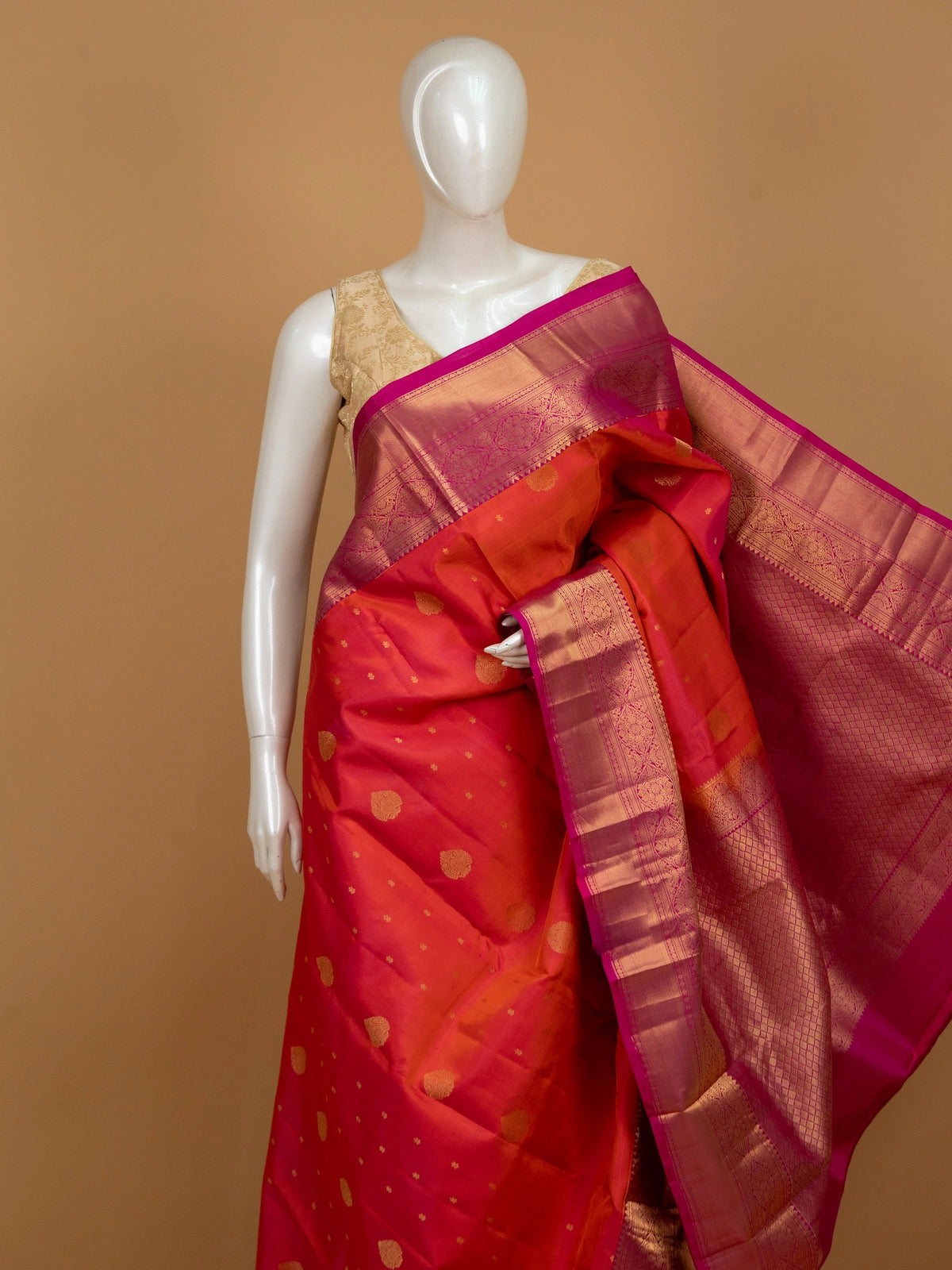 Orange pure Kanchipuram silk saree with contrast pink zari border and gold buttas