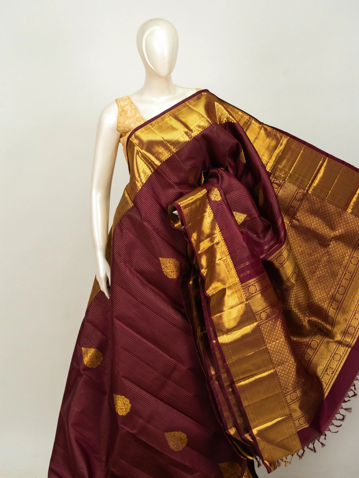 Maroon pure Kanchipuram silk saree with gold zari border, buttas and ornate woven pallu