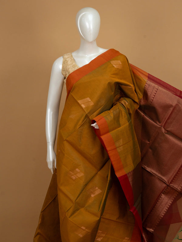 Mustard silk cotton saree with orange border, zari buttas, and a maroon copper-zari pallu