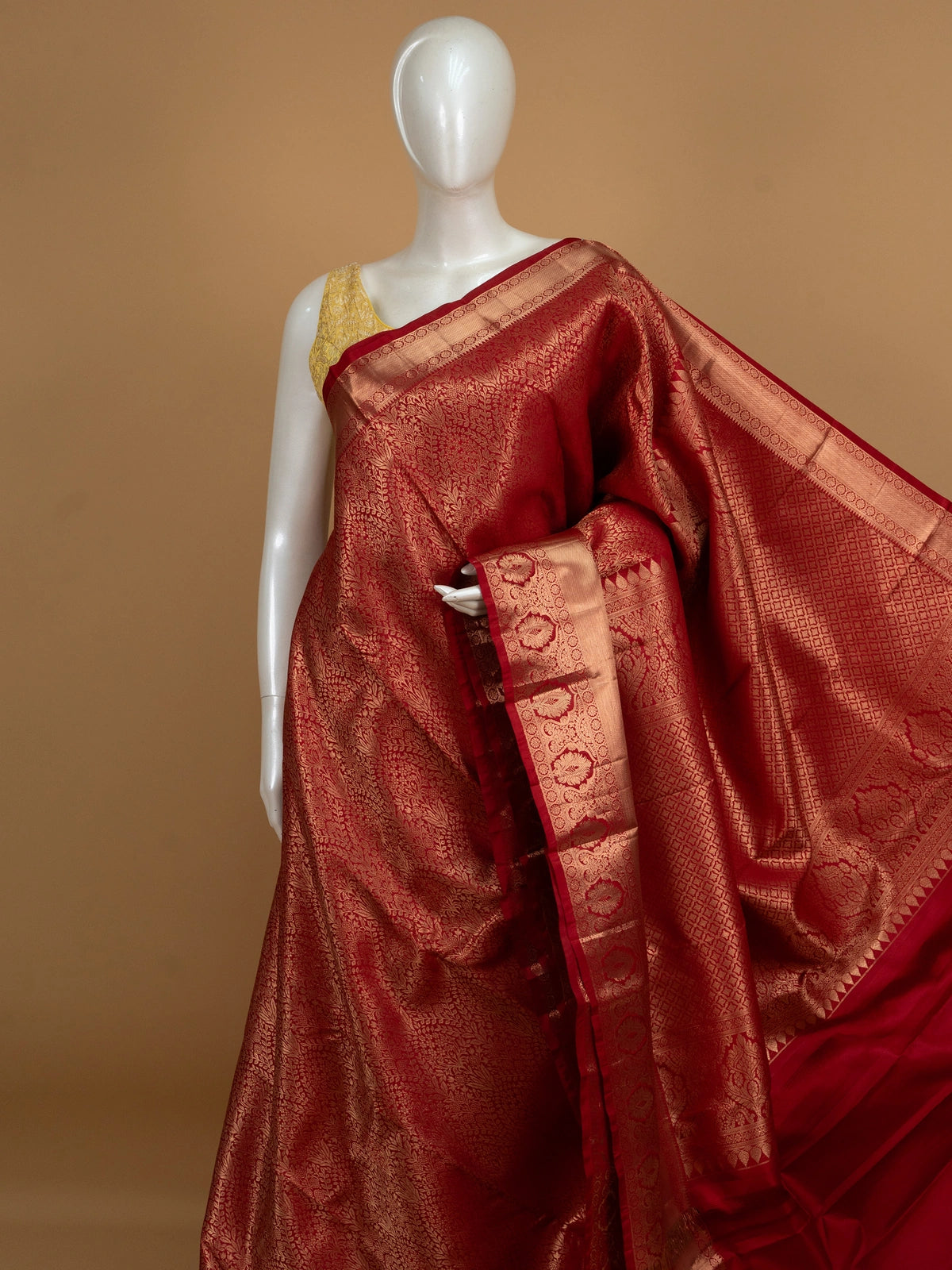 Red pure Kanchipuram silk saree with allover gold zari floral brocade and a broad temple-edged zari border