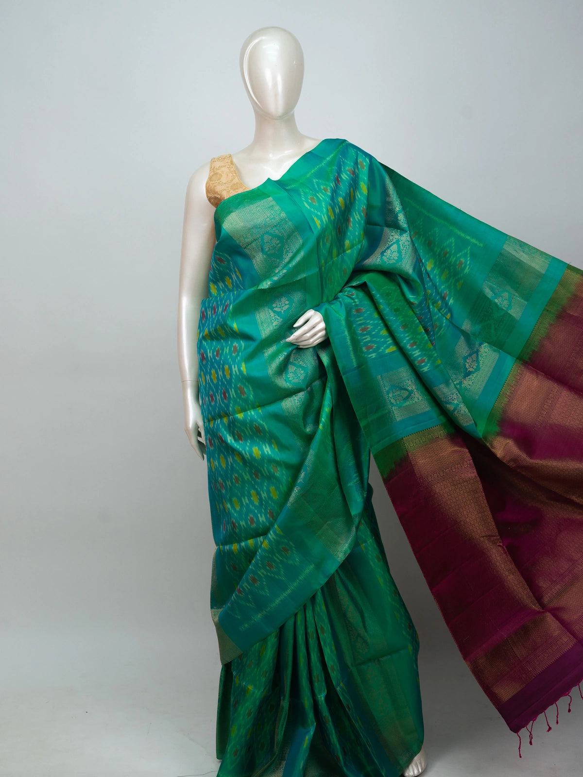 Teal green soft silk saree with ikat motifs, gold zari border and contrast magenta zari pallu