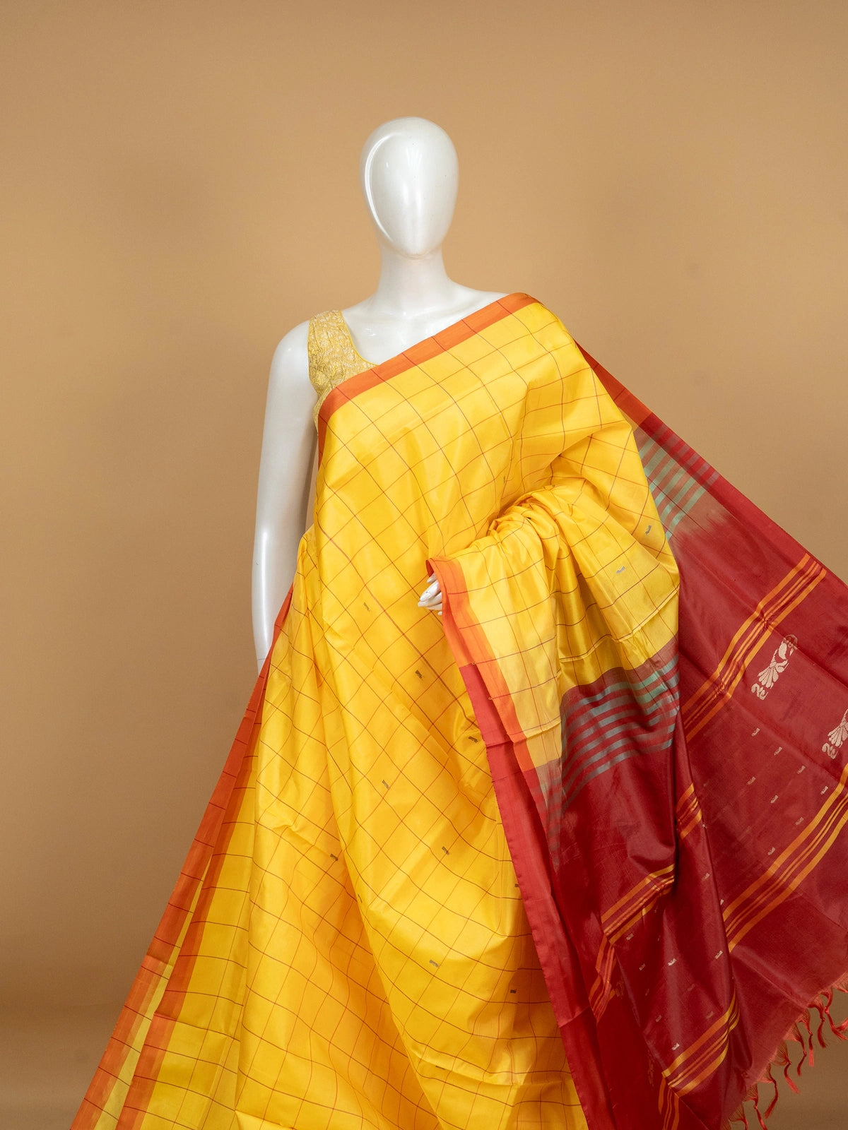 Yellow checked banana silk saree with contrast red zari pallu and coral blouse