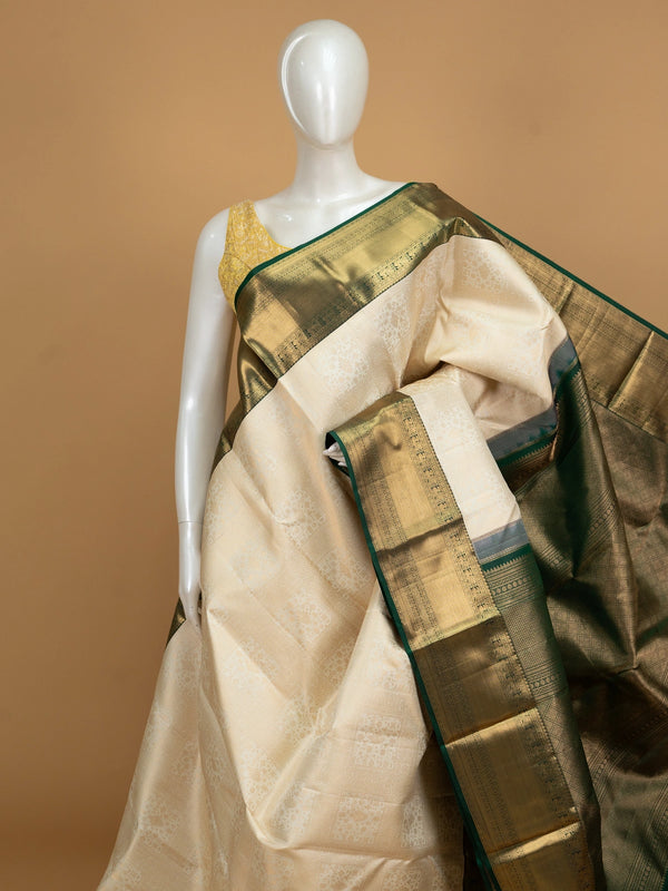 Cream pure Kanchipuram silk saree with gold zari brocade body and contrast dark green and gold border and pallu