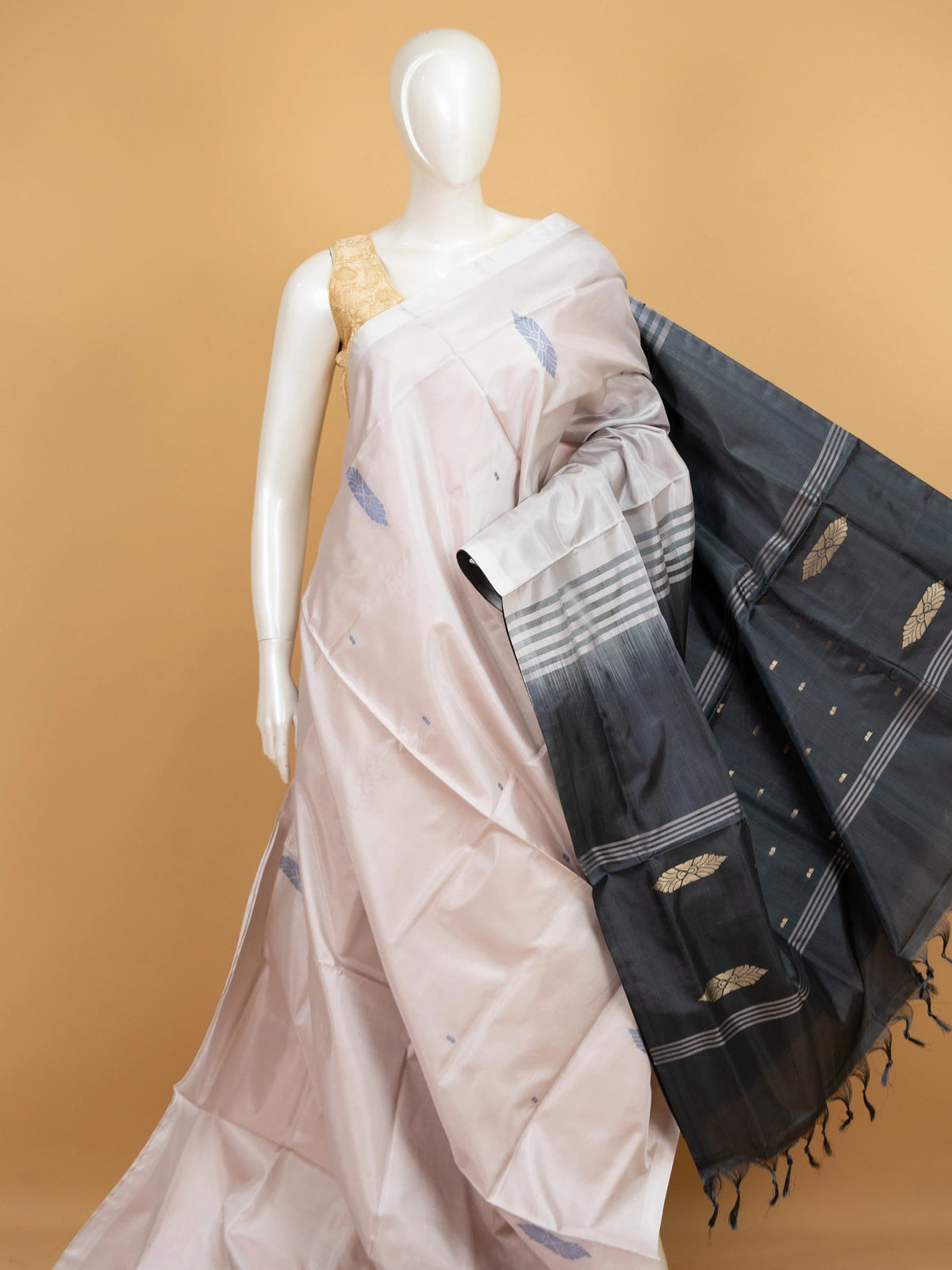 Blush beige Banana Silk saree with charcoal grey contrast pallu, gold zari leaf motifs and blue butta work