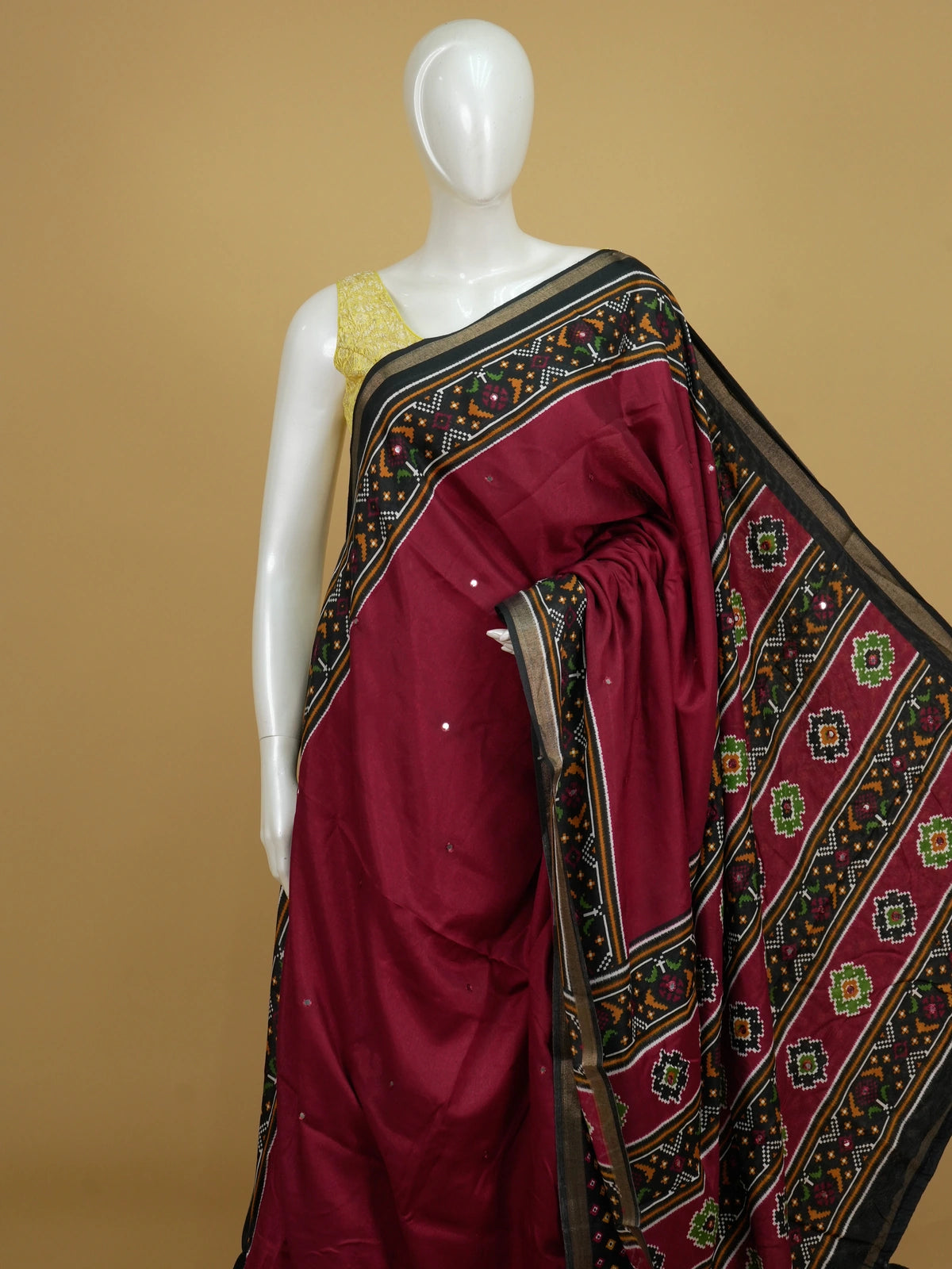 Maroon Dola silk saree with black patola-style border, multicolour pallu and mirror work
