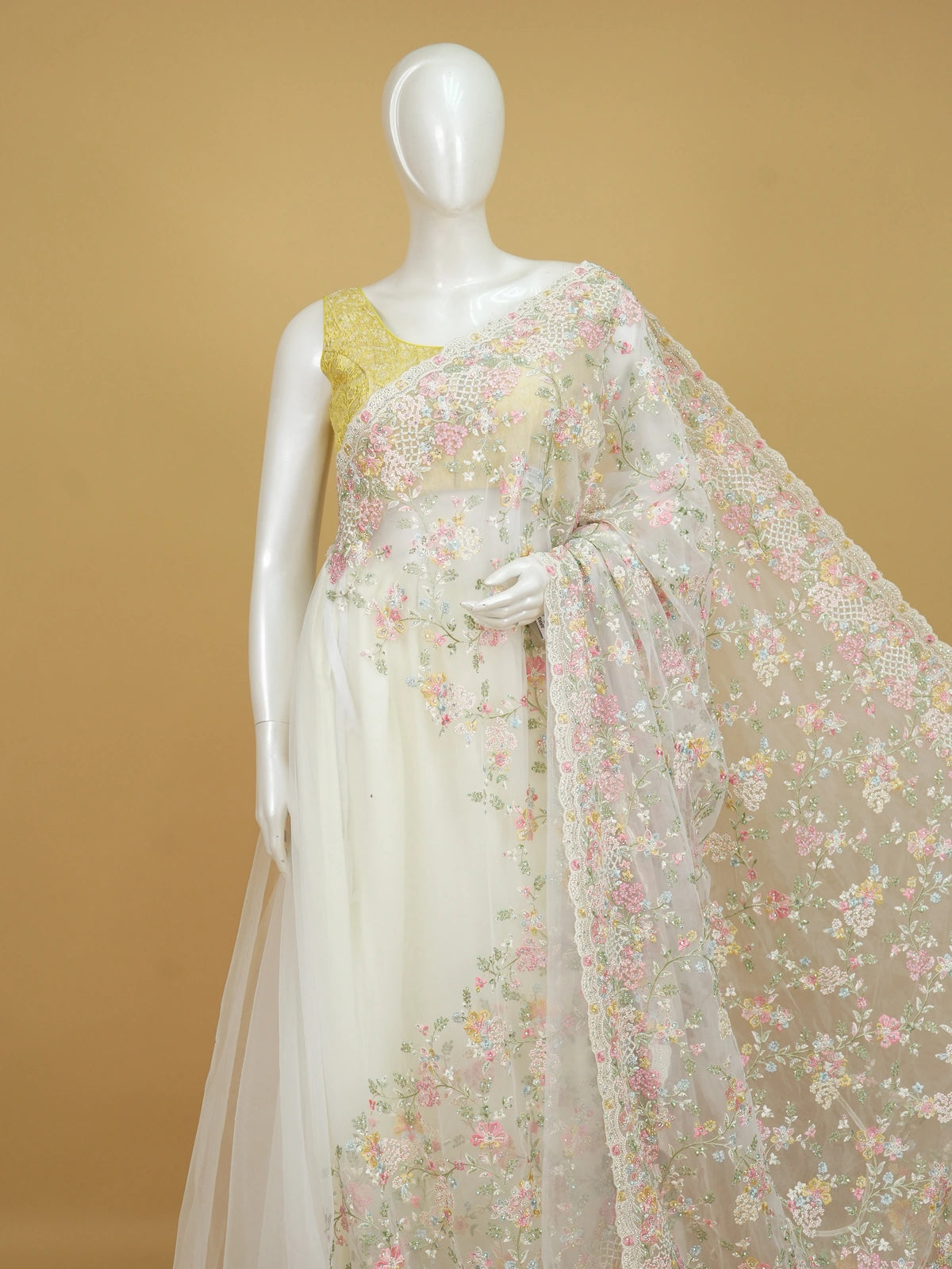Cream net designer saree with pastel multicolour floral embroidery and scalloped border