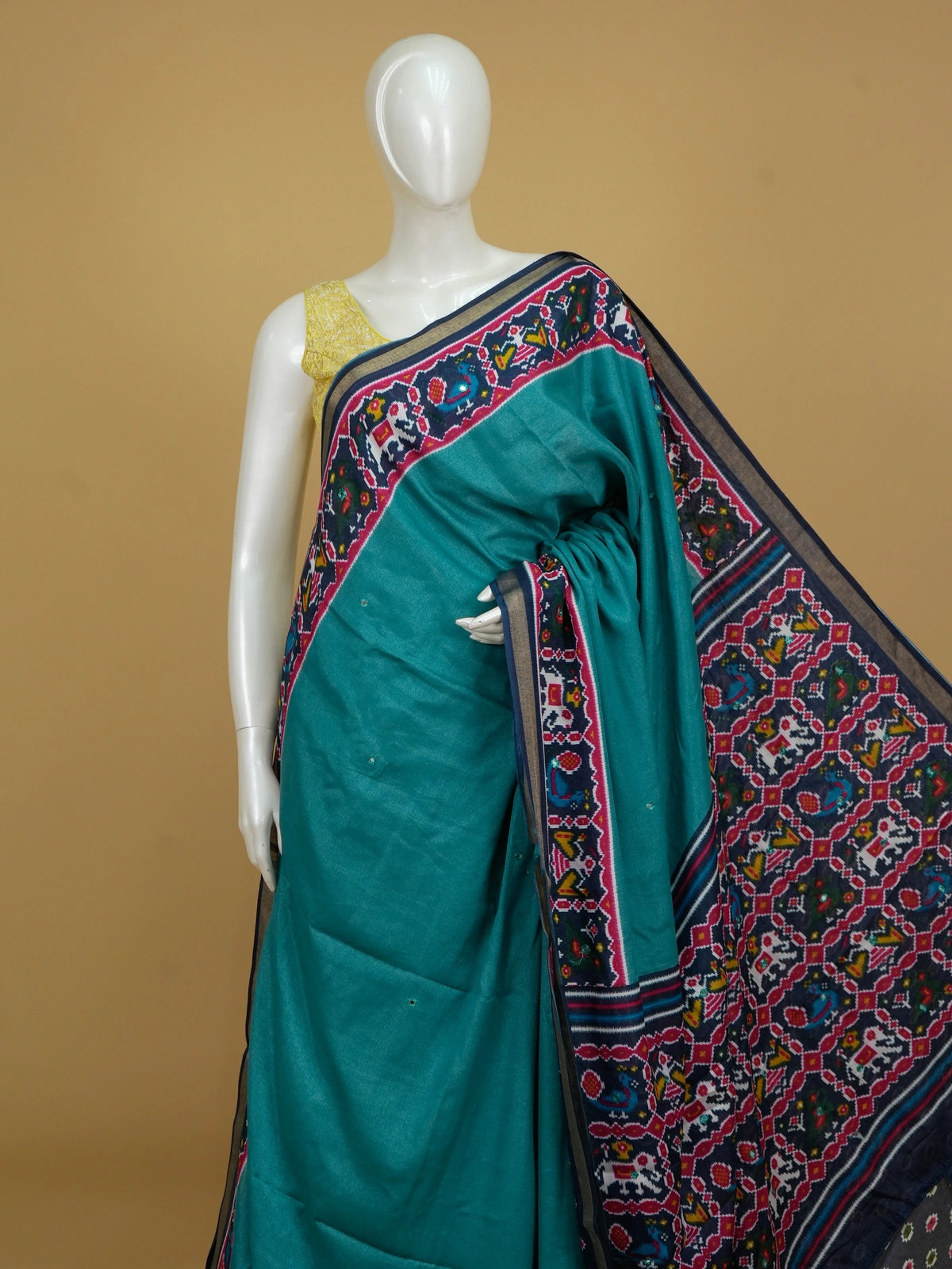 Teal linen cotton saree with navy and pink patola-style border, peacock and elephant motifs, and contrast blouse