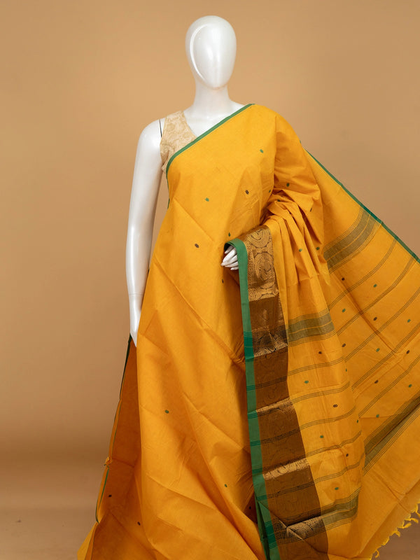 Mustard yellow Chettinad cotton saree with green contrast border, gold zari peacock motifs and woven buttis