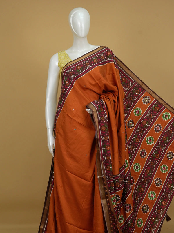 Rust orange linen cotton saree with patola-print brown border, mirror-work buttis and contrast blouse