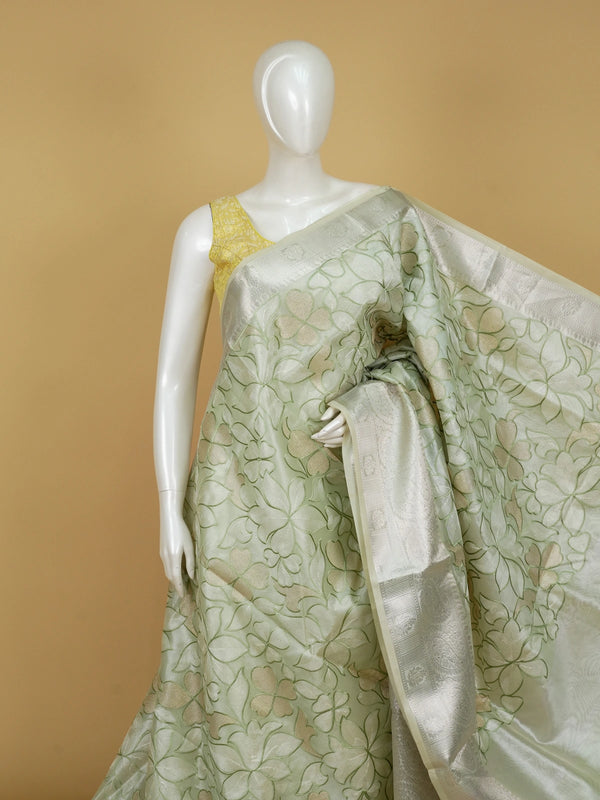 Sage green designer saree with cream-gold floral embroidery and silver zari border