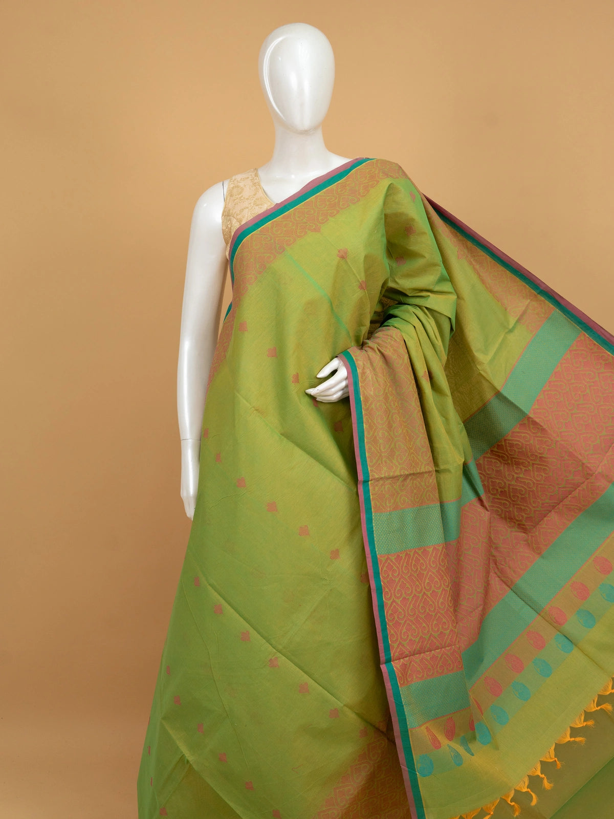 Parrot green silk cotton saree with coral pink contrast border, gold zari motifs, and woven paisley pallu