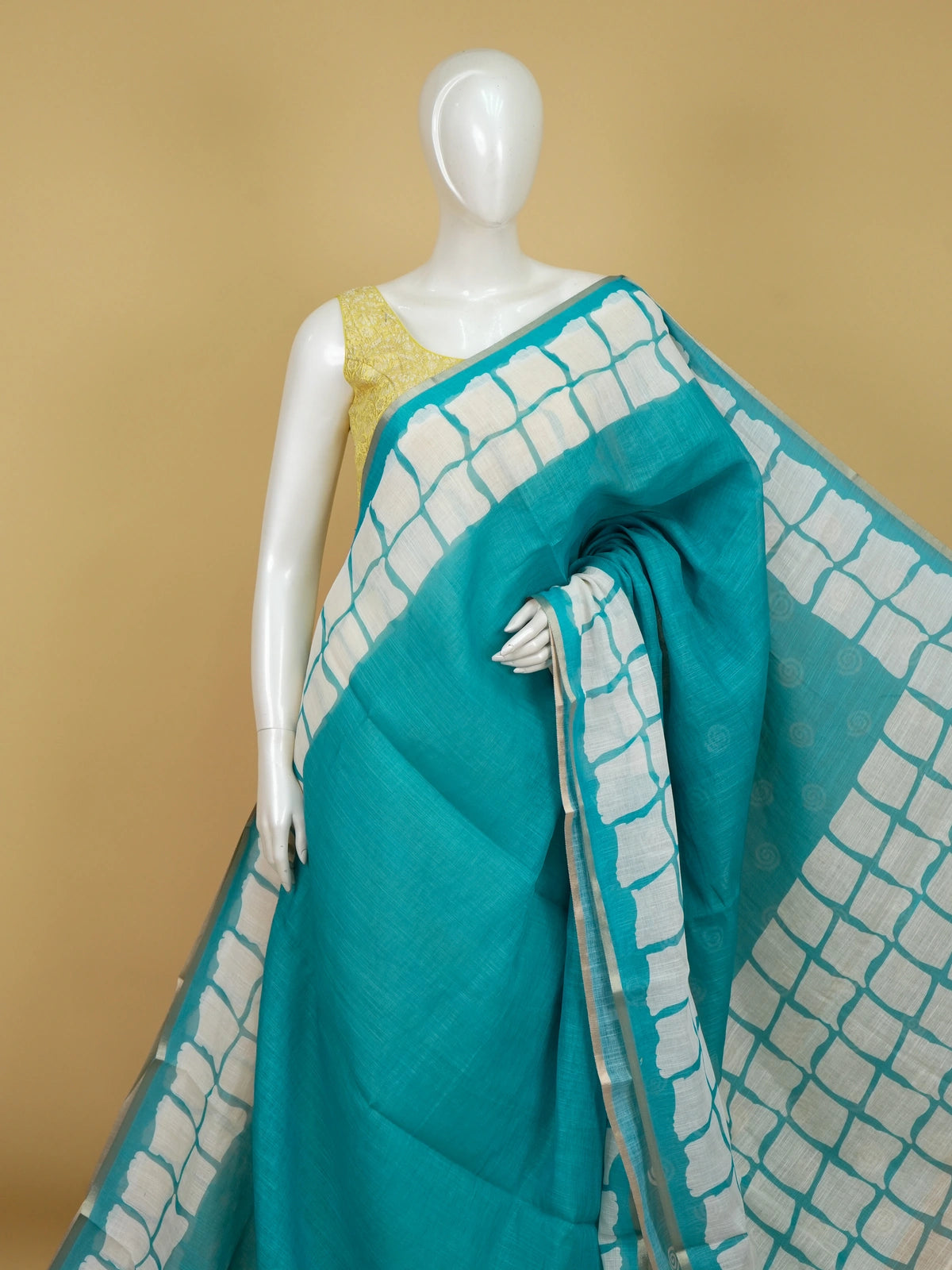 Teal and off-white linen cotton saree with batik grid border and white spiral motifs