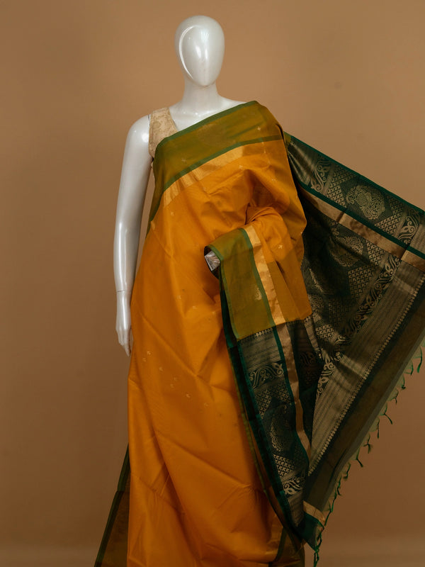 Mustard yellow silk cotton saree with green gold zari border and peacock pallu