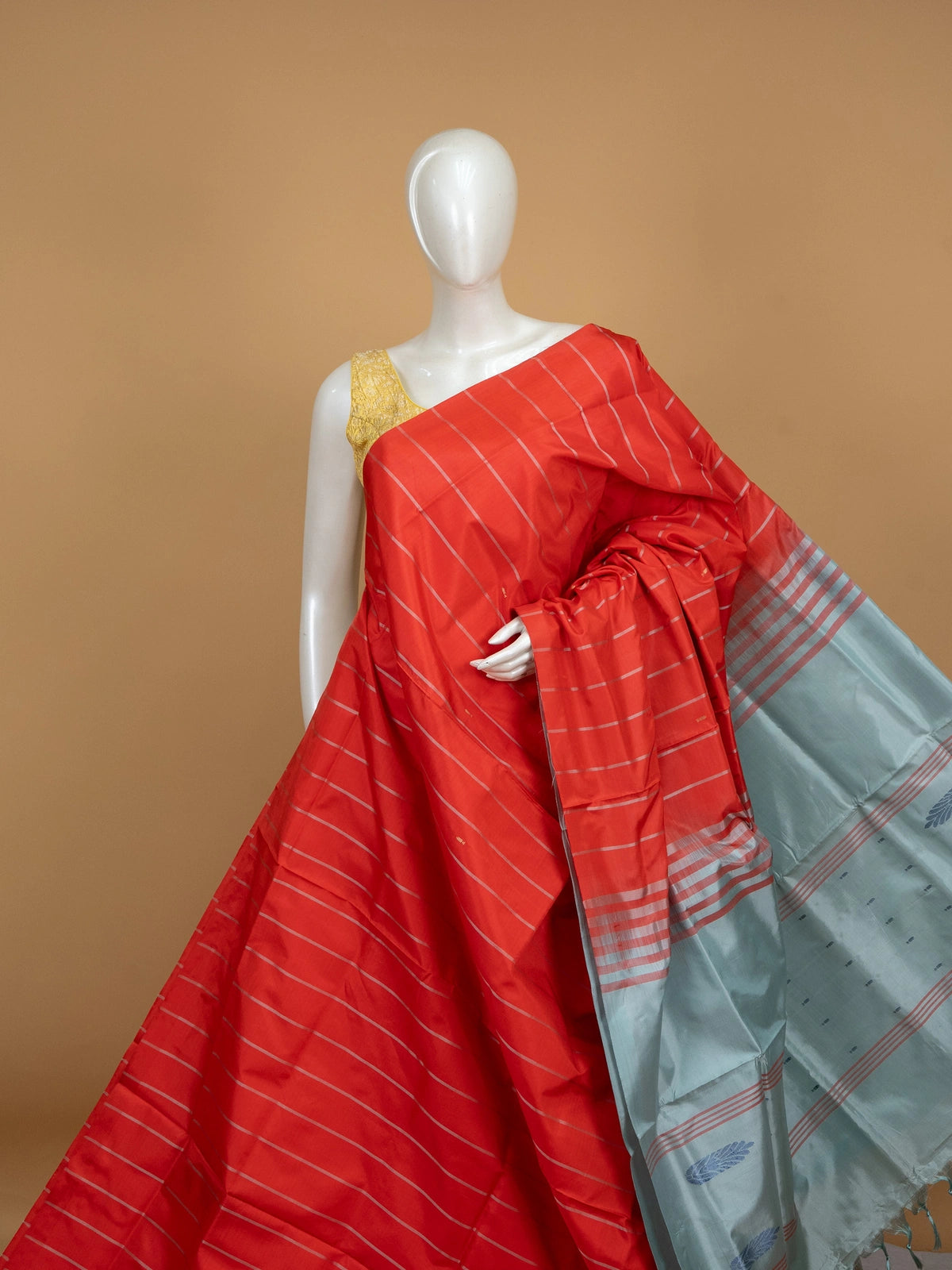 Orange-red banana silk saree with silver zari stripes and a contrast grey-blue pallu