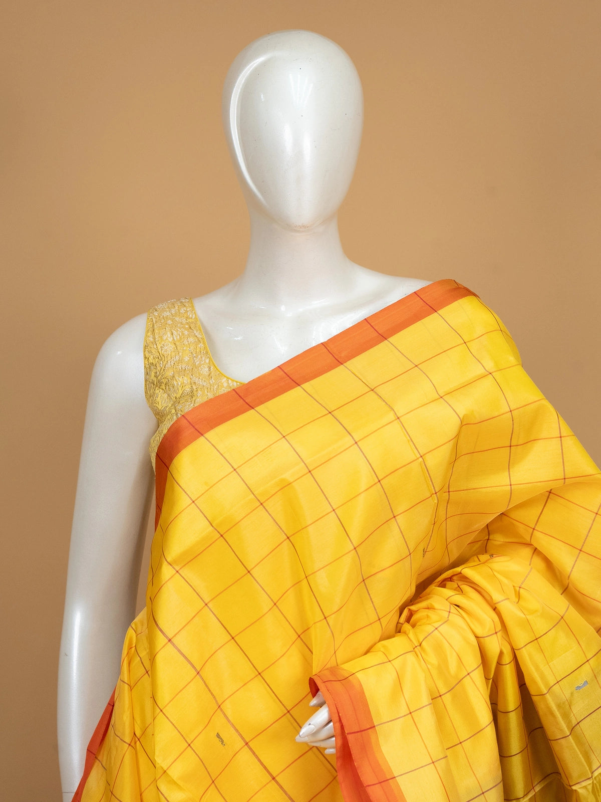 Yellow checked banana silk saree with contrast red zari pallu and coral blouse
