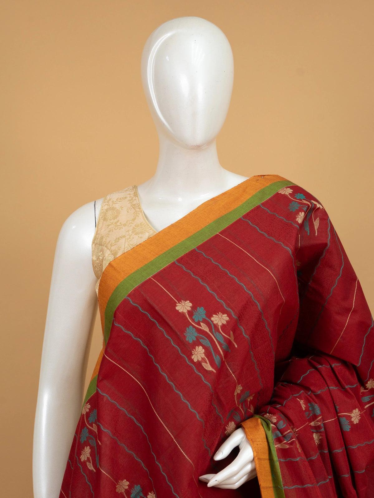 Maroon red silk cotton saree with orange contrast border, floral woven motifs and decorative pallu