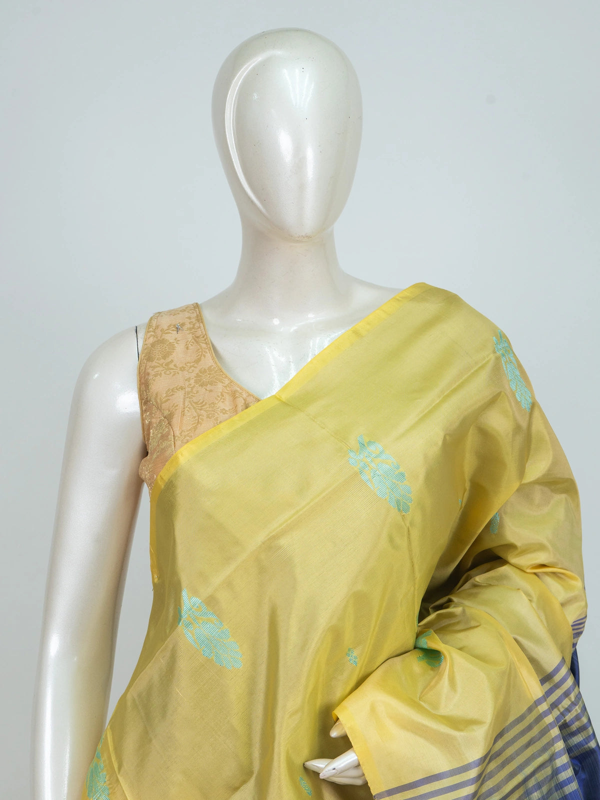 Yellow banana silk saree with navy blue contrast pallu, turquoise buttas and gold zari striped border