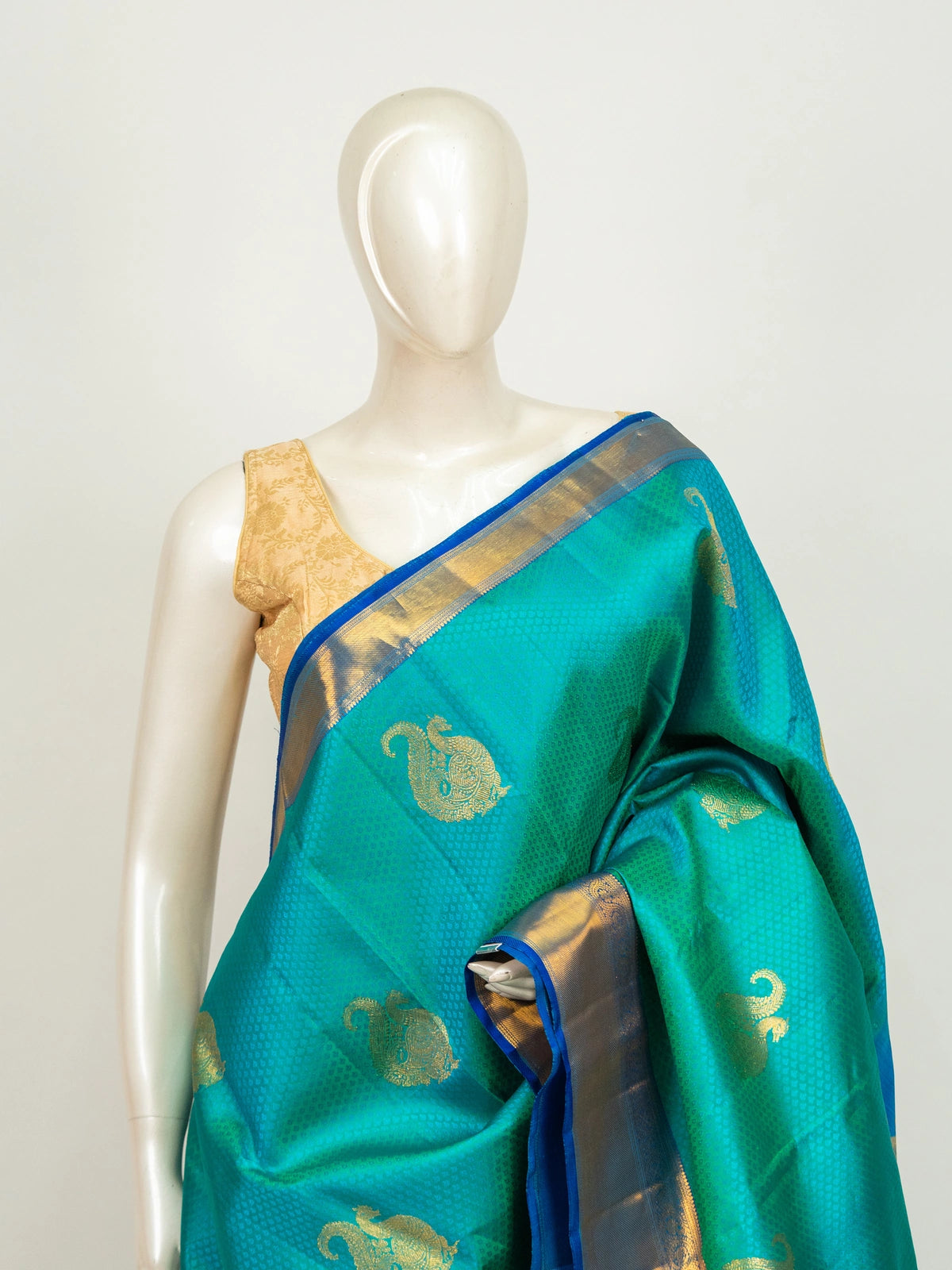 Teal green pure Kanchipuram silk saree with royal blue contrast border and gold zari paisley motifs