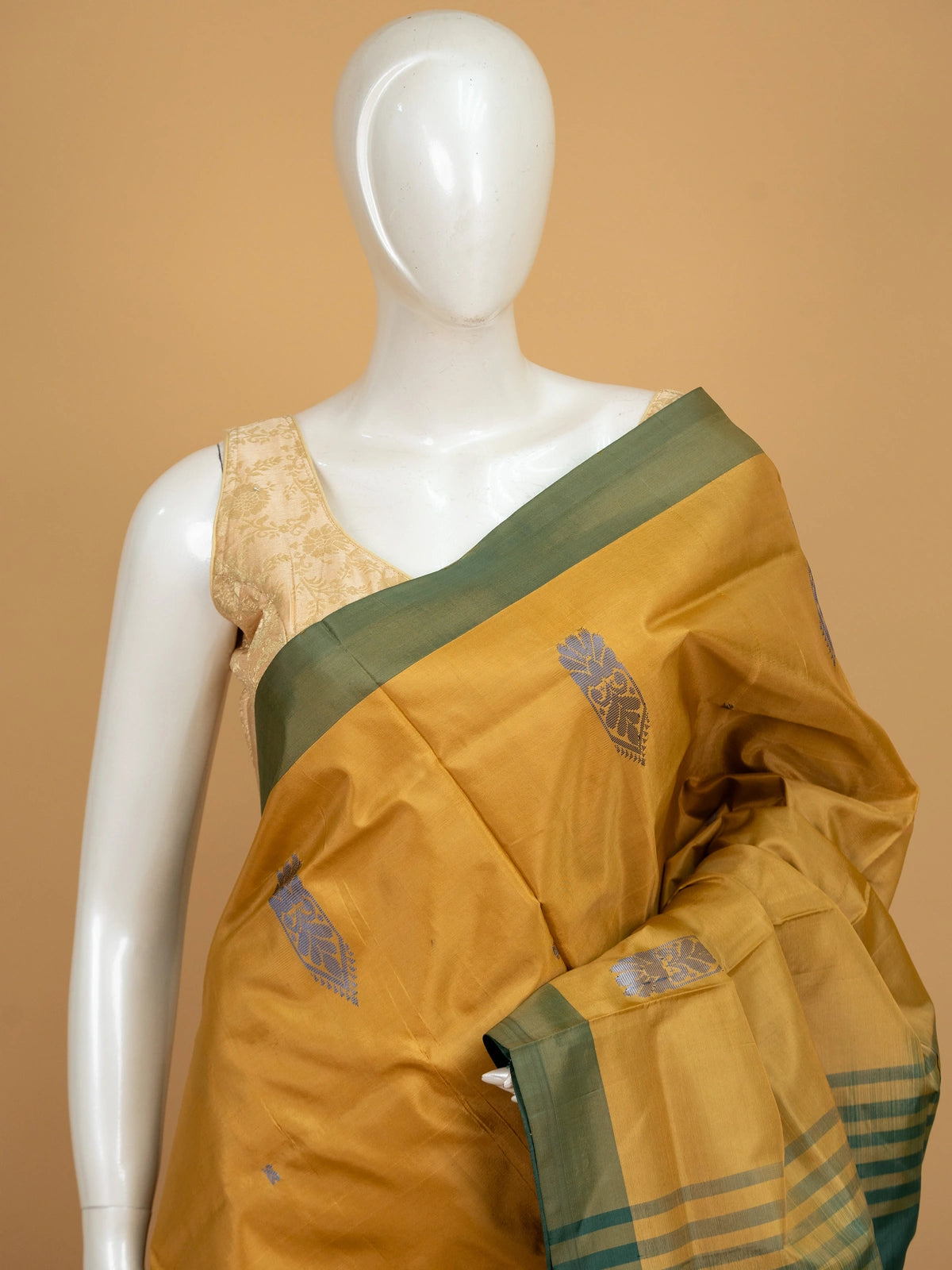 Mustard banana silk saree with contrast bottle-green border, gold zari buttas and striped tasselled pallu