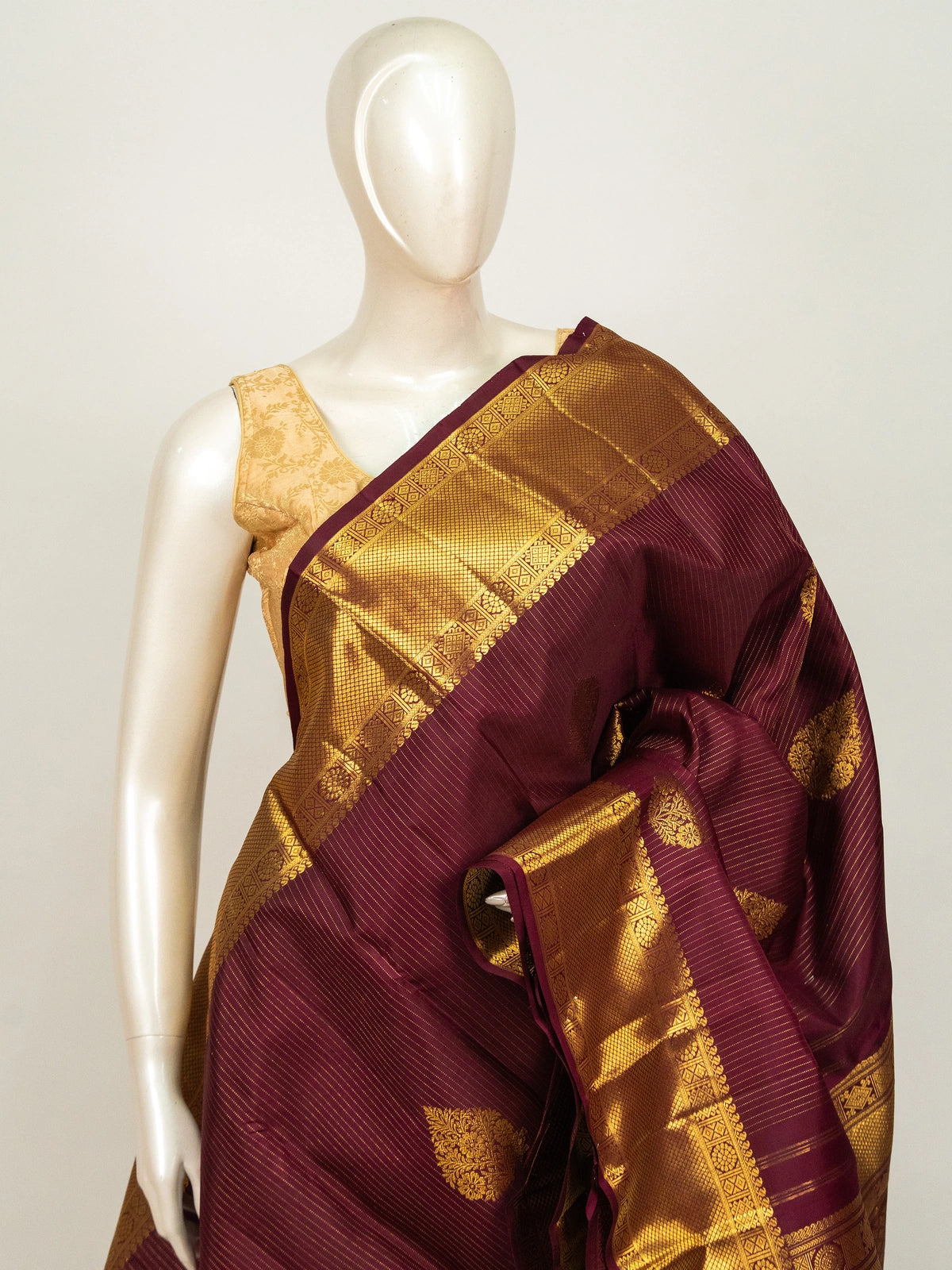 Maroon pure Kanchipuram silk saree with gold zari border, buttas and ornate woven pallu