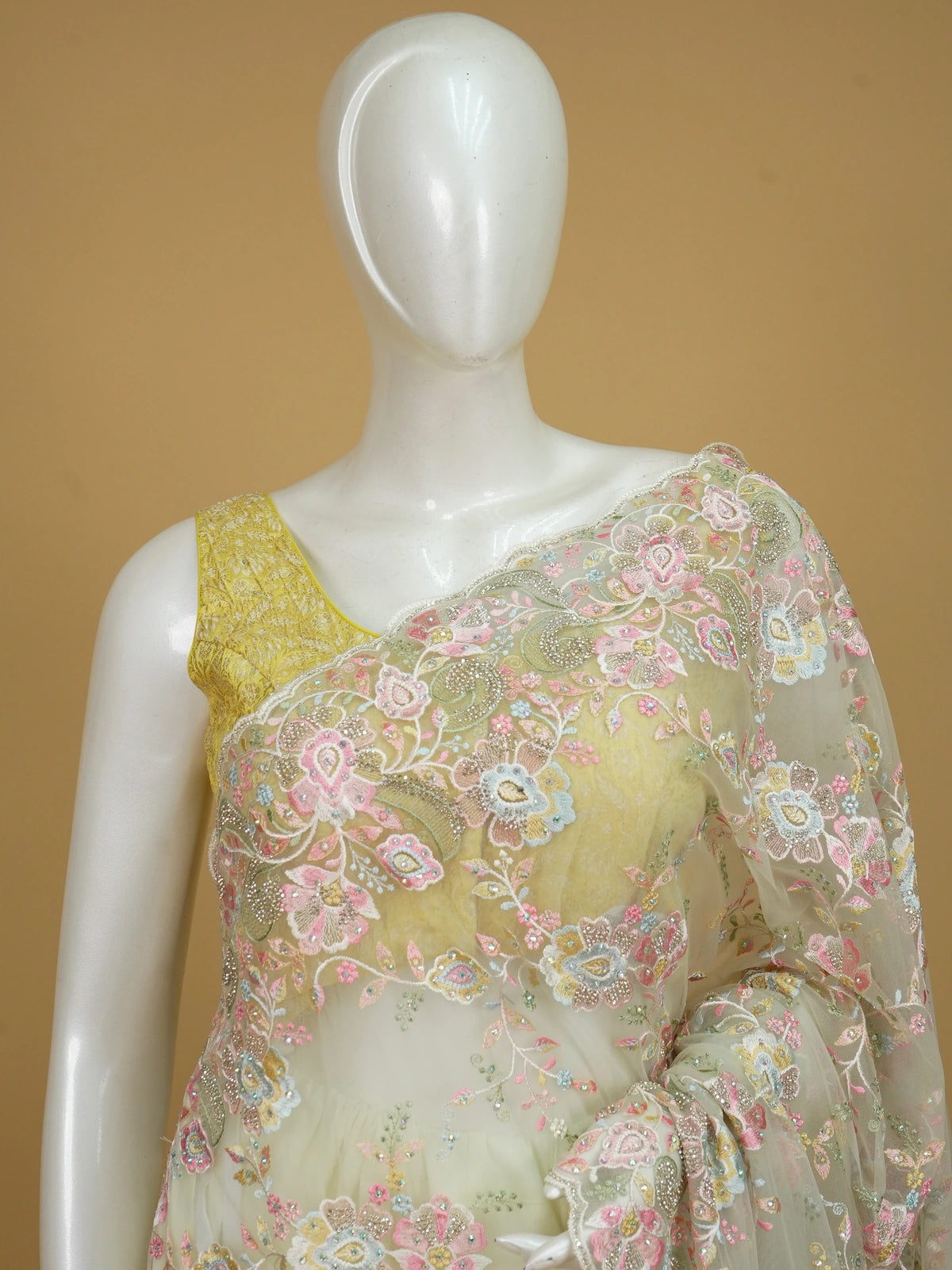 Cream net designer saree with pastel multicolour floral embroidery and scalloped border