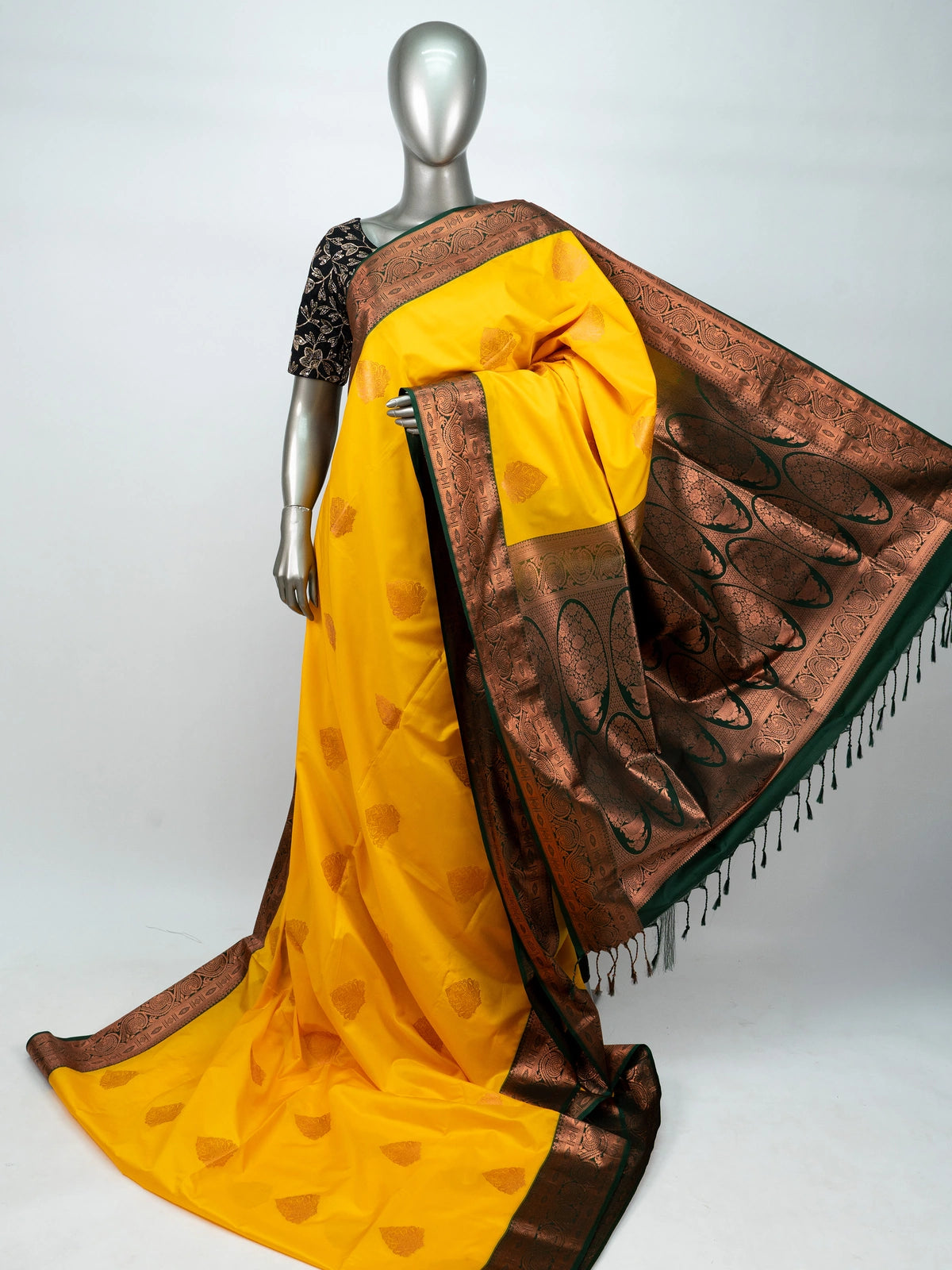 Yellow semi silk saree with dark green contrast border, copper zari buttas and black floral blouse
