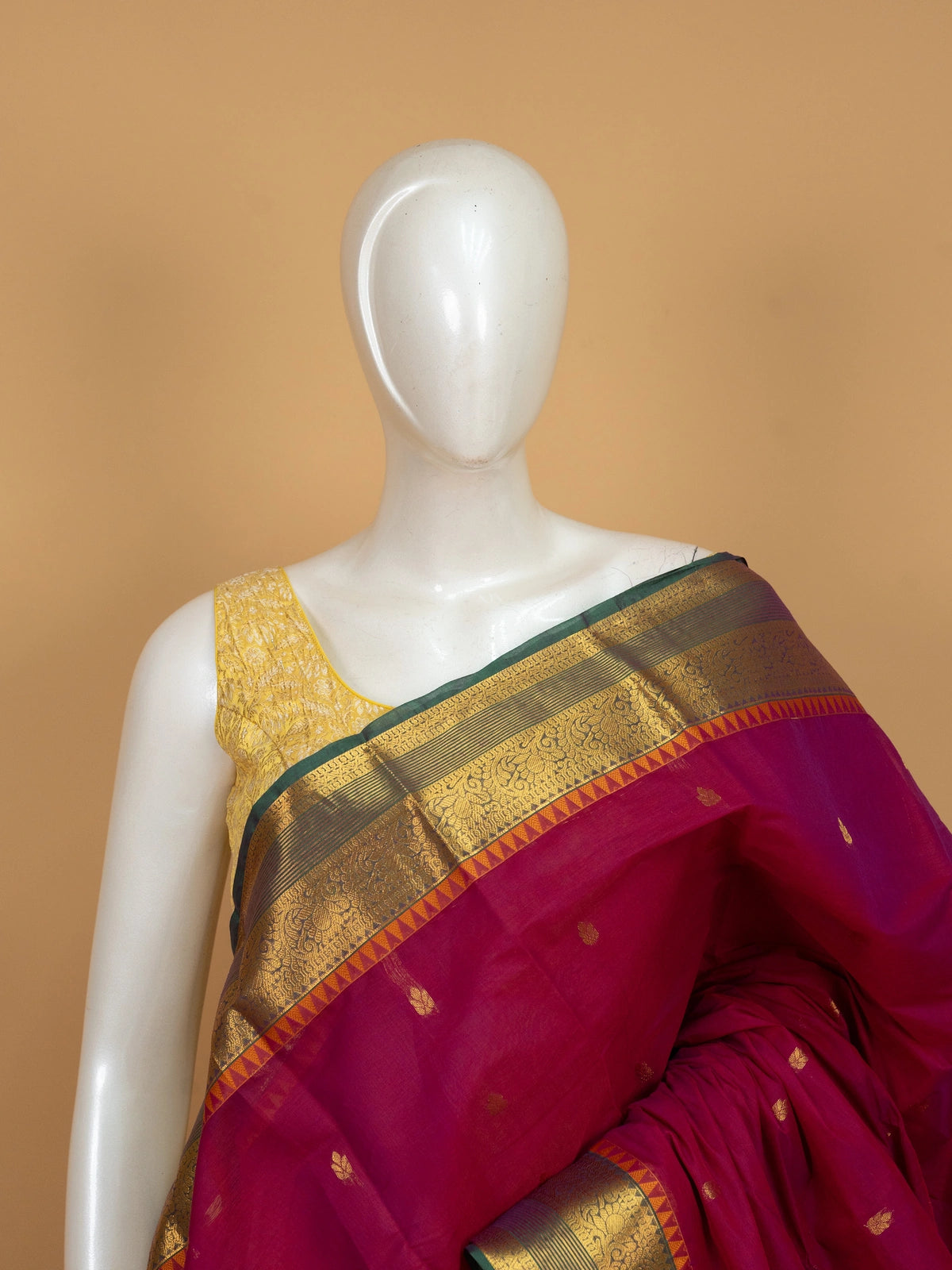 Pink Chettinad cotton saree with contrast green-and-gold zari border, gold buttas, and ornate gold pallu