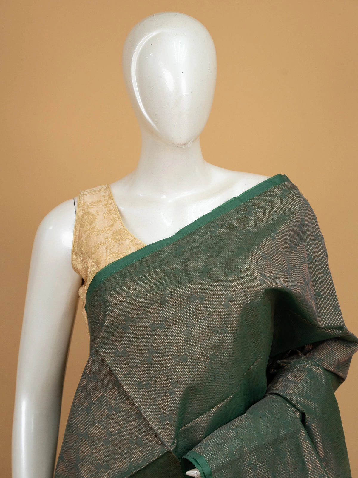 Dark green silk cotton saree with copper-gold zari border and geometric woven pallu