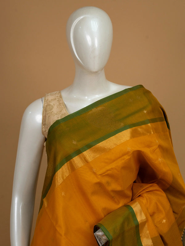 Mustard yellow silk cotton saree with green gold zari border and peacock pallu