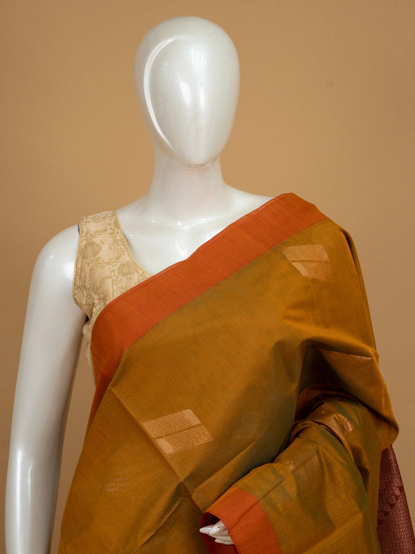 Mustard silk cotton saree with orange border, zari buttas, and a maroon copper-zari pallu