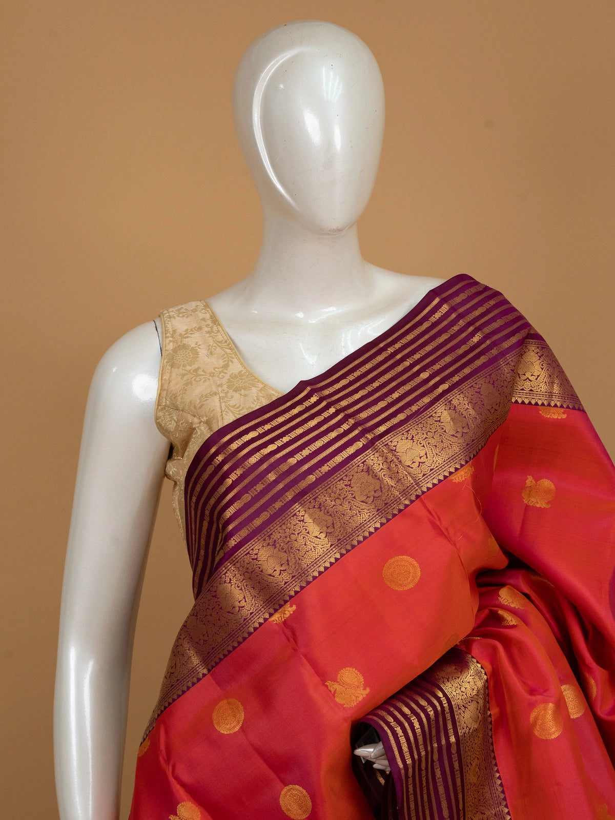 Orange-red pure Kanchipuram silk saree with gold zari buttas and contrast purple zari border and pallu