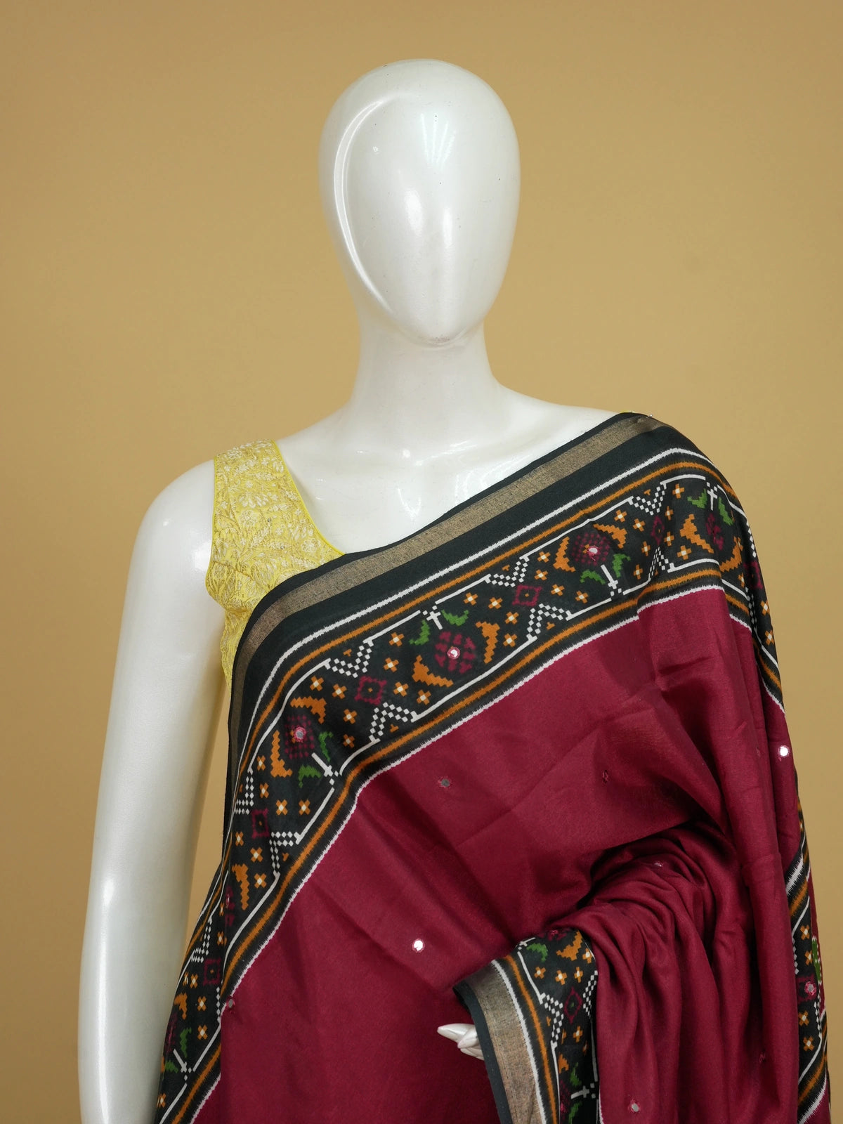 Maroon Dola silk saree with black patola-style border, multicolour pallu and mirror work