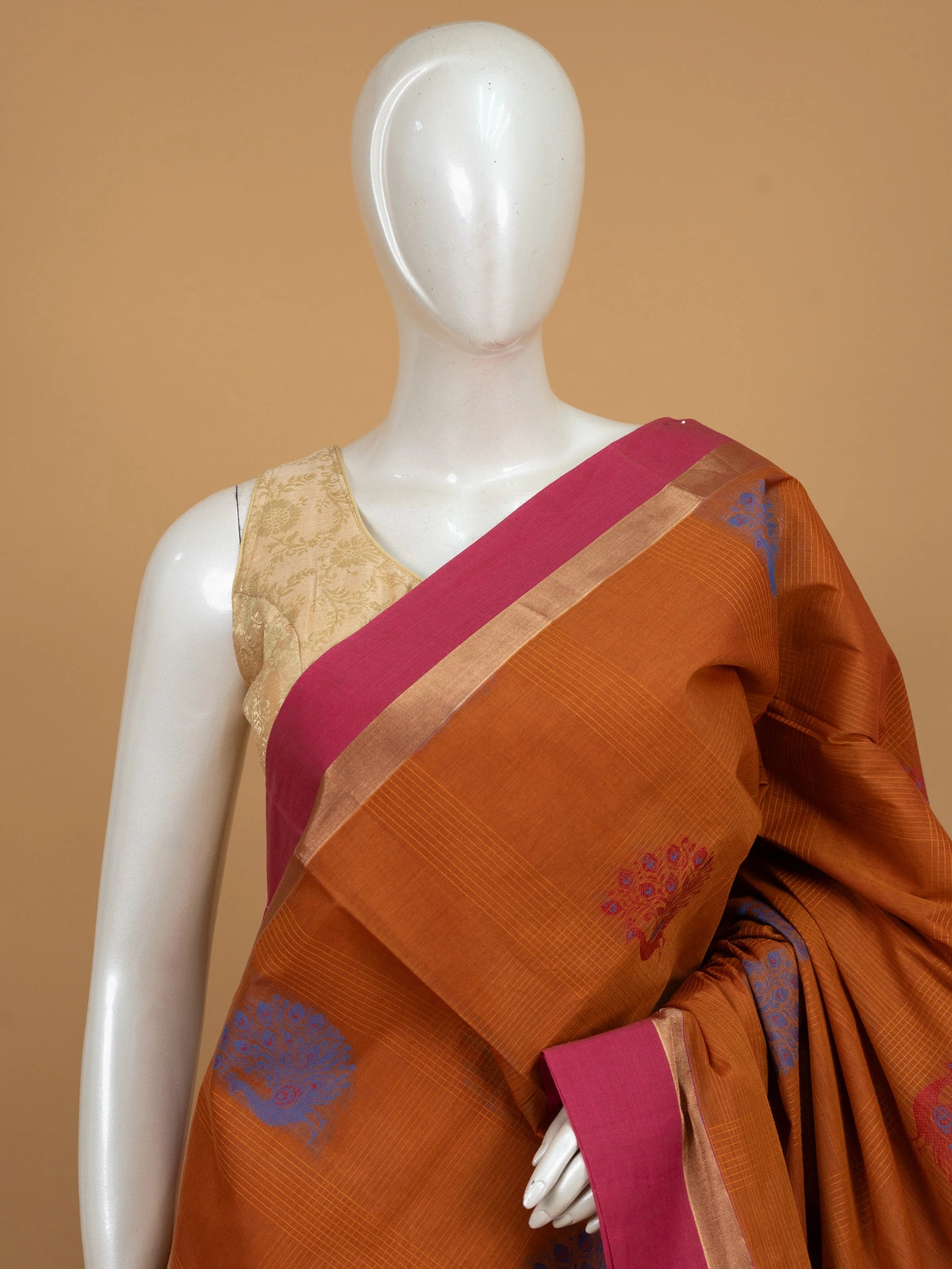 Rust orange silk cotton saree with pink zari border and blue and red peacock motifs
