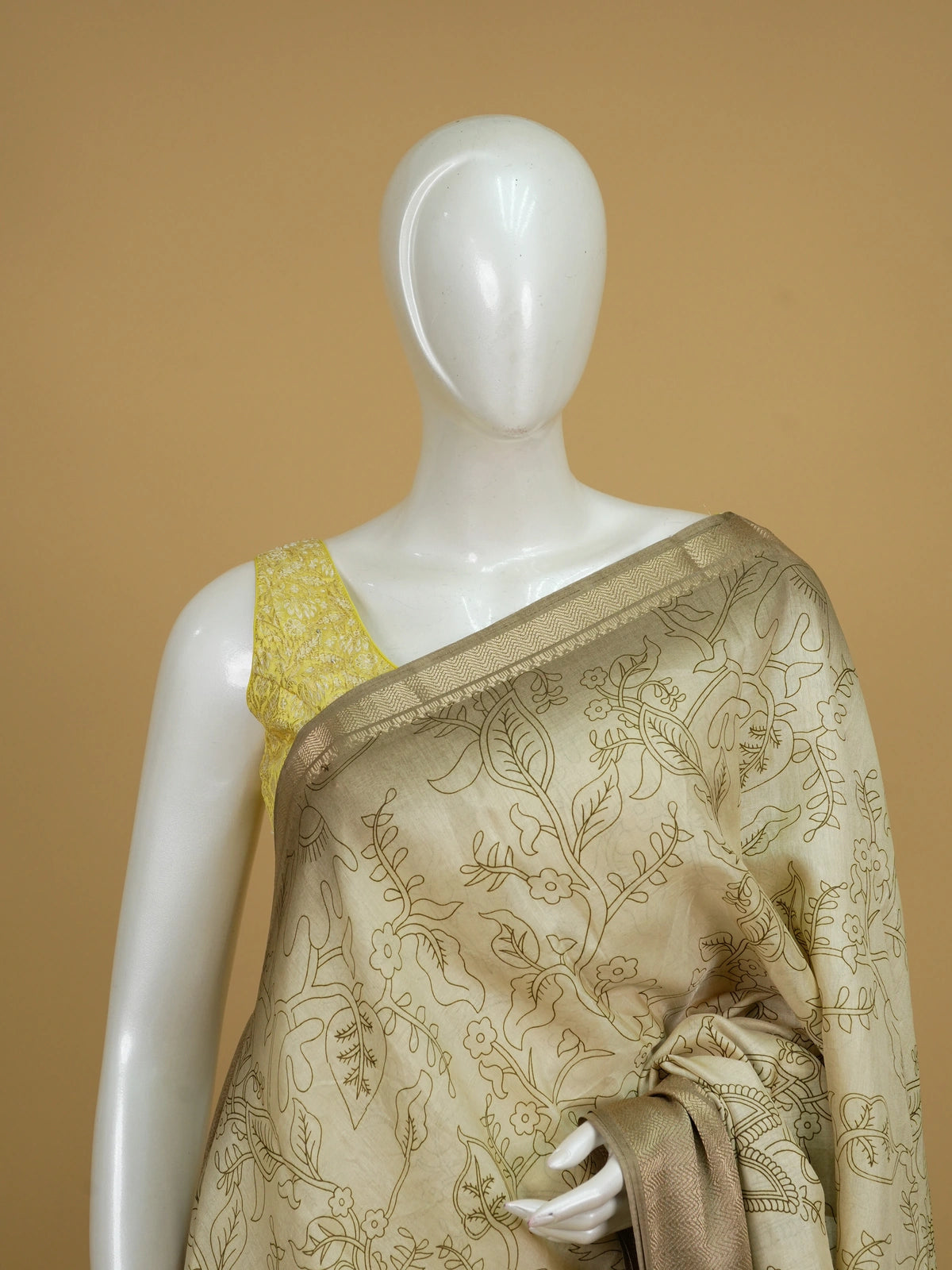 Cream Dola silk saree with Kalamkari-style floral print, peacock pallu and gold zari border