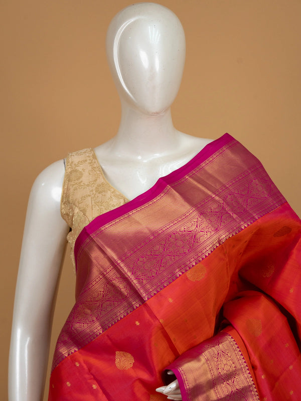 Orange pure Kanchipuram silk saree with contrast pink zari border and gold buttas