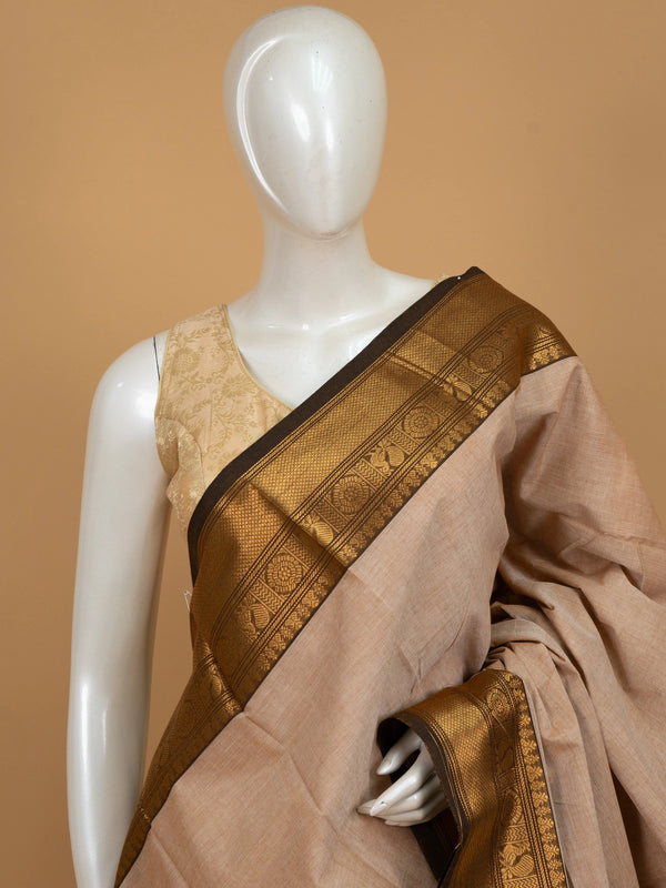 Beige Chettinad cotton saree with dark brown and gold zari peacock motif border