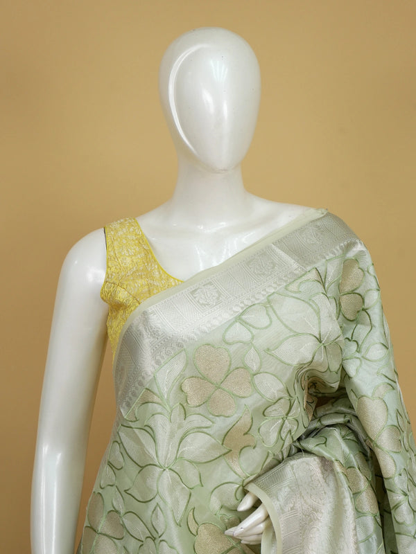 Sage green designer saree with cream-gold floral embroidery and silver zari border