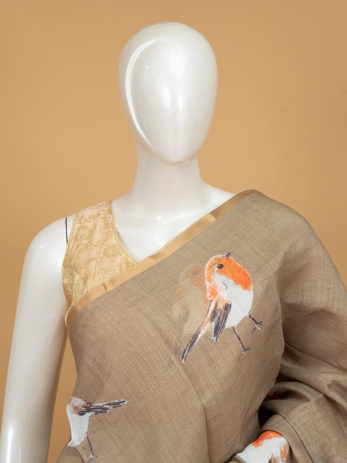 Beige linen cotton saree with orange robin bird prints and a golden zari border