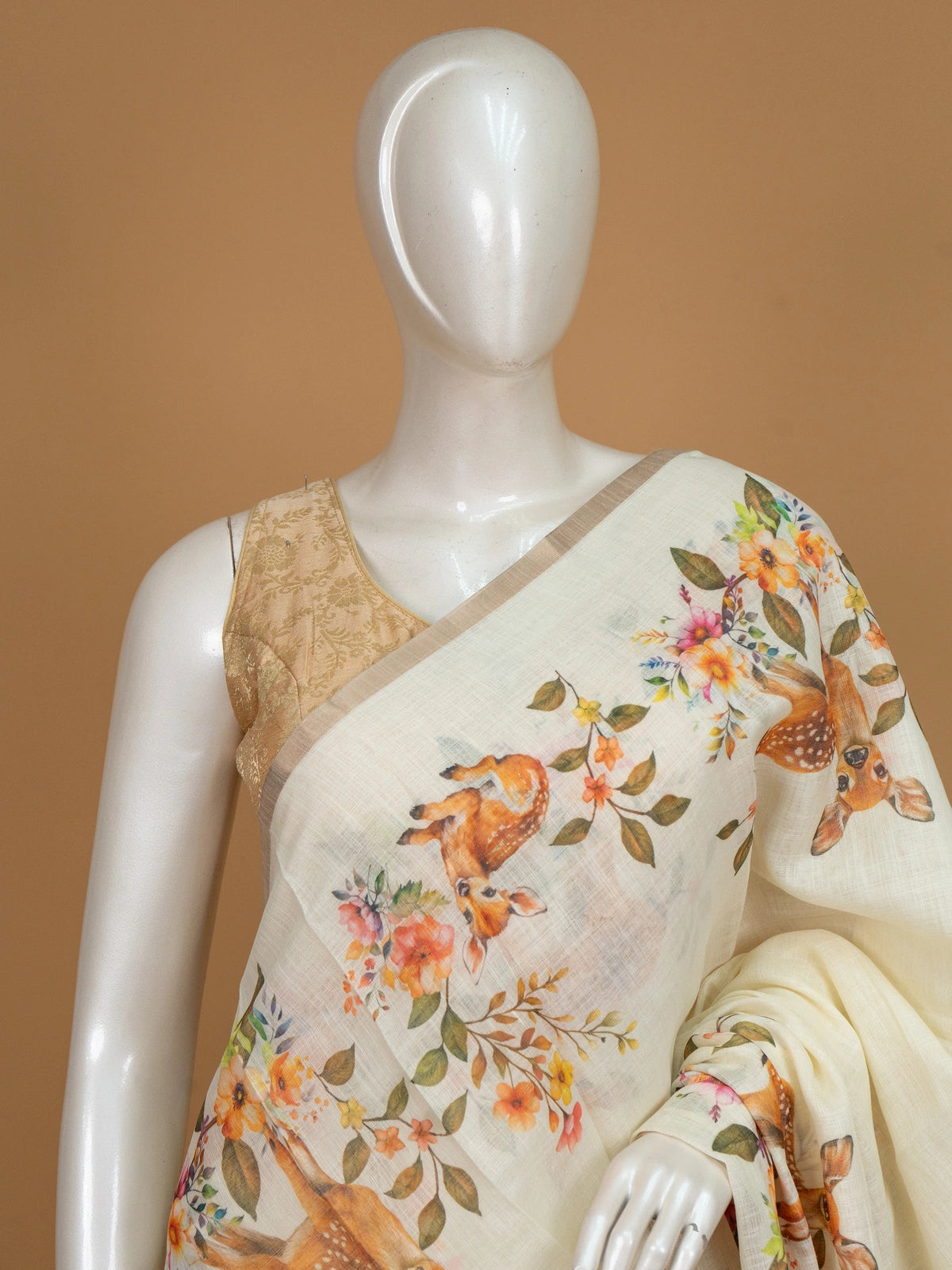 Cream linen cotton saree with orange floral and spotted deer prints and a slim golden zari border