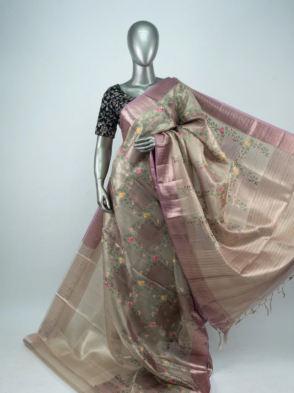 Beige linen cotton saree with mauve pink zari border, multicoloured floral embroidery and a black contrast blouse