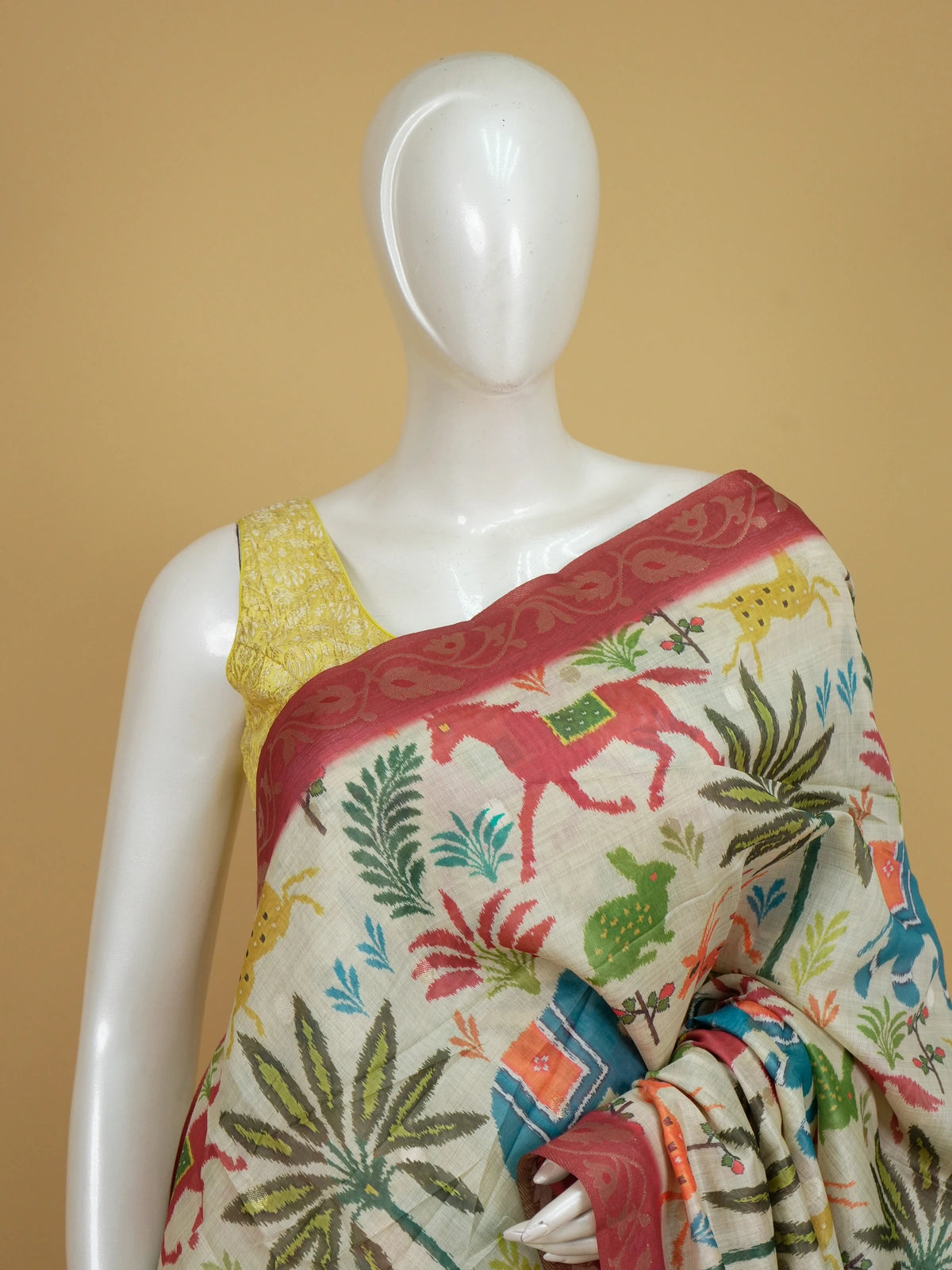 Cream linen cotton saree with multicolour Patola-style animal print and contrast red zari border