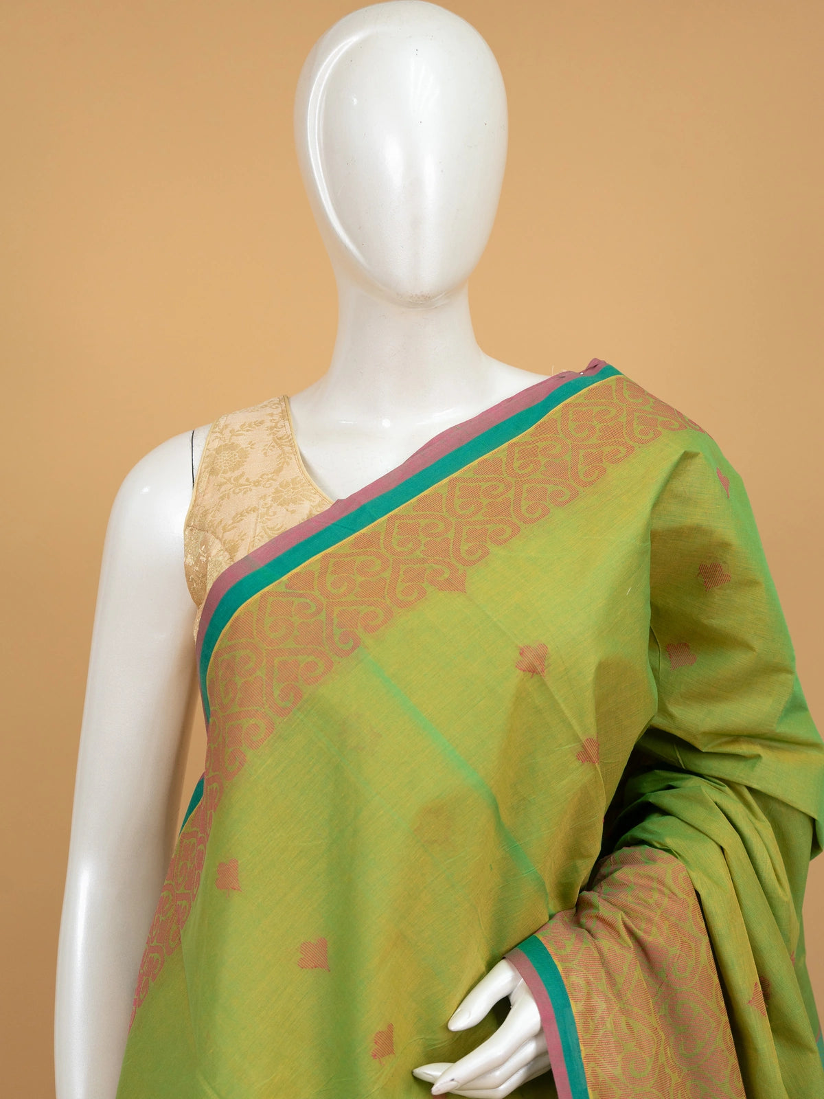 Parrot green silk cotton saree with coral pink contrast border, gold zari motifs, and woven paisley pallu