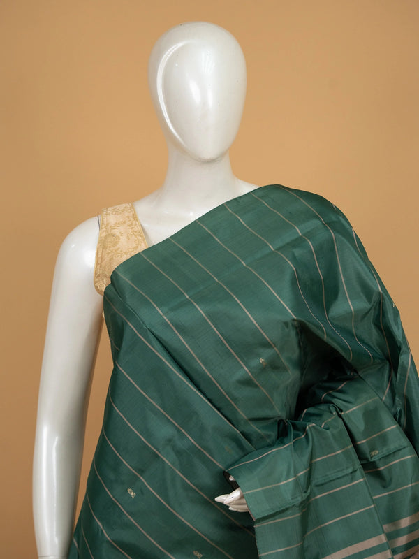Dark green banana silk saree with gold zari stripes and contrast peach pallu with blue floral motifs