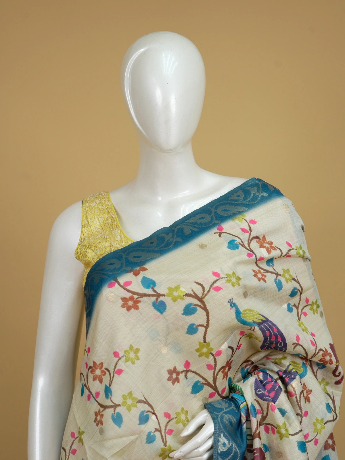 Cream linen cotton saree with peacock and elephant motifs and a teal silver zari border